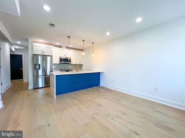 kitchen with tasteful backsplash, light wood-type flooring, kitchen peninsula, white cabinets, and stainless steel appliances