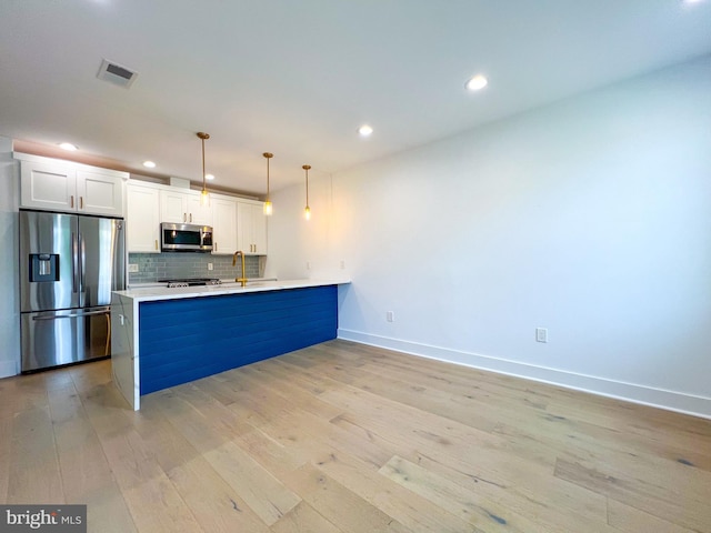 kitchen featuring white cabinetry, kitchen peninsula, light hardwood / wood-style flooring, and stainless steel appliances