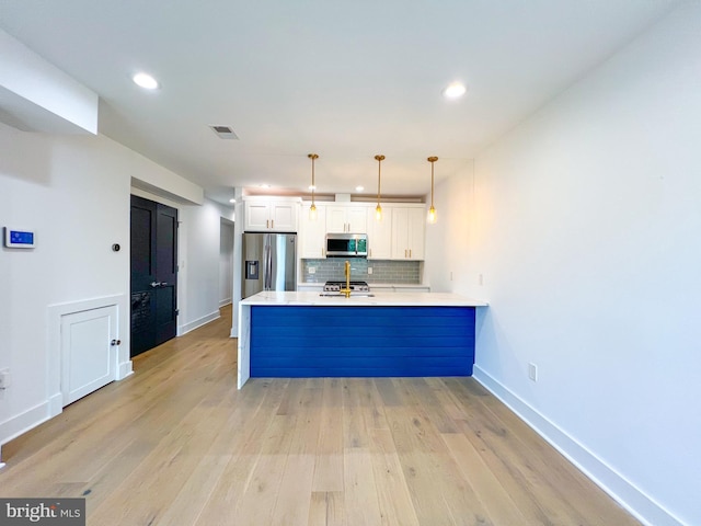 kitchen with white cabinetry, light wood-type flooring, kitchen peninsula, backsplash, and appliances with stainless steel finishes