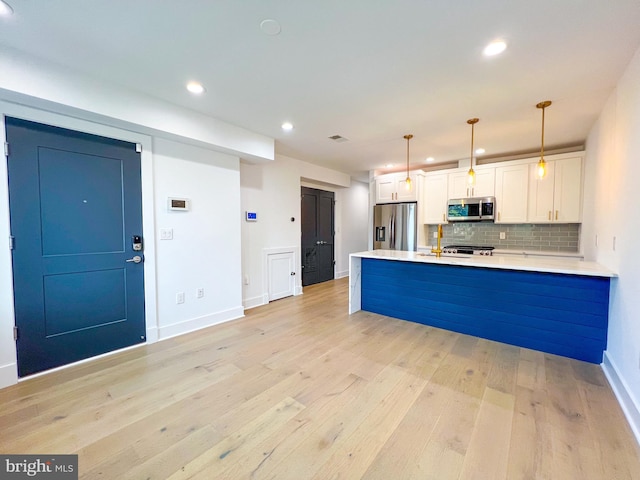 kitchen with appliances with stainless steel finishes, light hardwood / wood-style floors, and white cabinetry