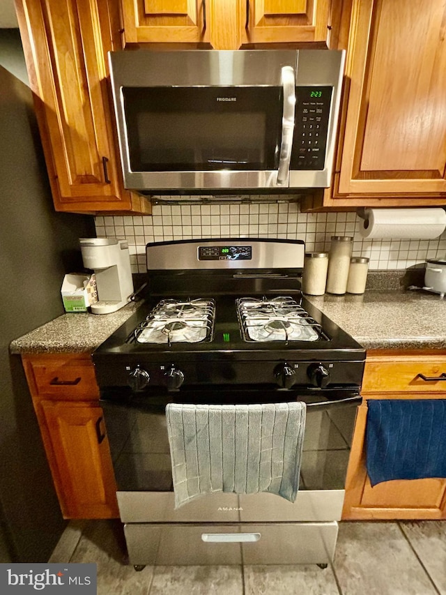 kitchen with light tile patterned floors, decorative backsplash, and gas stove