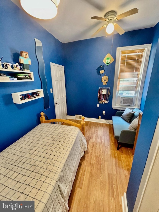 bedroom featuring cooling unit, light hardwood / wood-style flooring, and ceiling fan