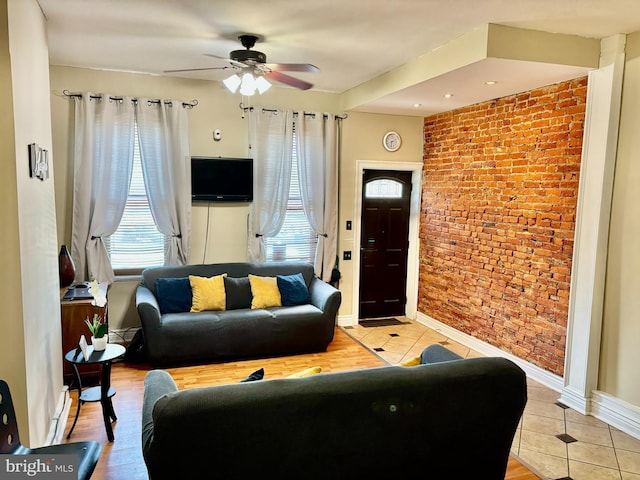 living room with light tile patterned floors, ceiling fan, and brick wall