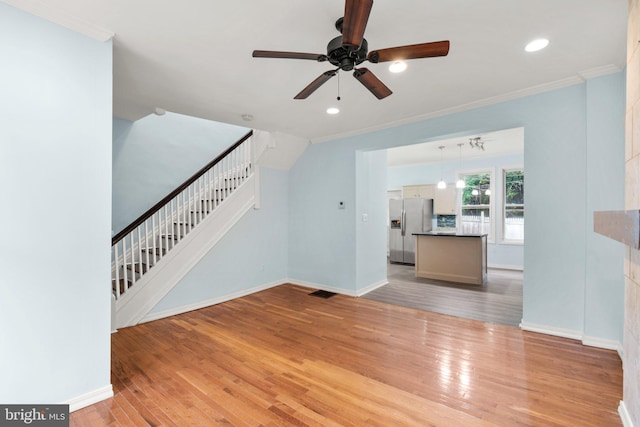 unfurnished living room featuring ornamental molding, ceiling fan, and light wood-type flooring