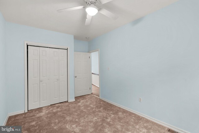 unfurnished bedroom with ceiling fan, light colored carpet, and a closet