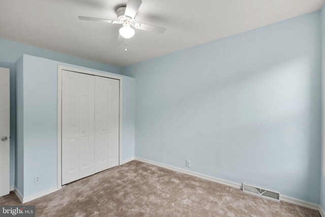 unfurnished bedroom with light colored carpet, ceiling fan, and a closet