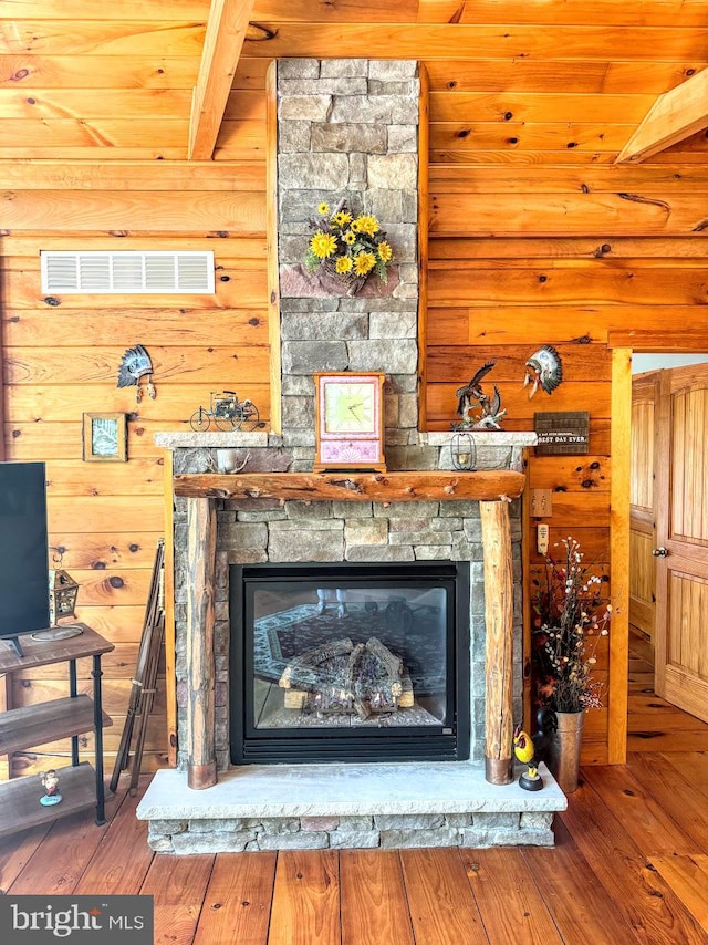 interior details with a stone fireplace, beam ceiling, and hardwood / wood-style flooring