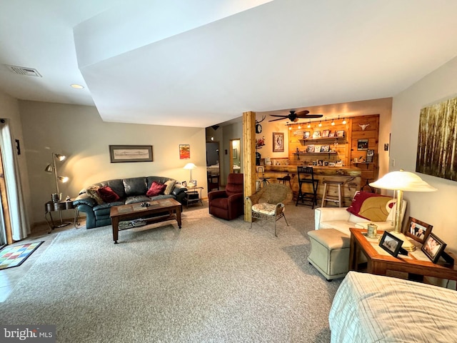 carpeted living room featuring bar area and ceiling fan