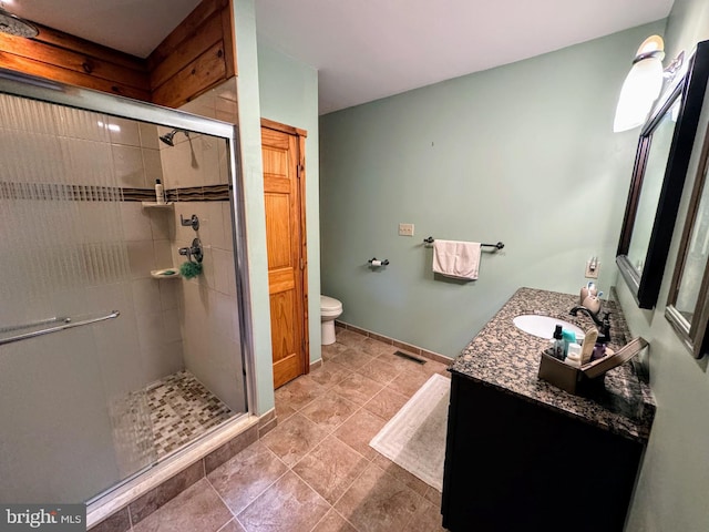 bathroom with tile patterned floors, a shower with door, toilet, and vanity