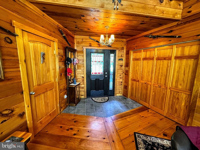 entryway featuring an inviting chandelier, wood walls, wooden ceiling, and wood-type flooring