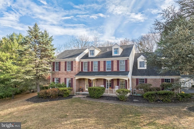 colonial house featuring a front yard and covered porch