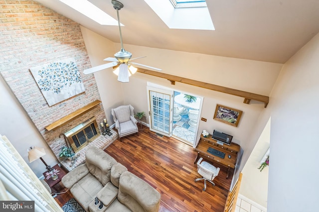 living room featuring wood-type flooring, a skylight, and high vaulted ceiling