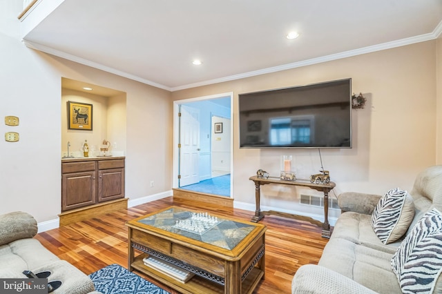 living room featuring sink, light hardwood / wood-style floors, and ornamental molding