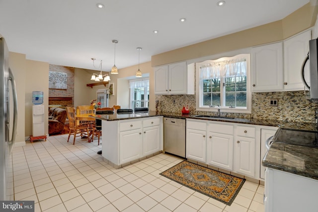 kitchen featuring pendant lighting, kitchen peninsula, sink, appliances with stainless steel finishes, and white cabinetry