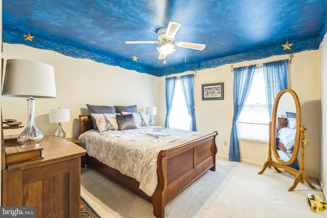 bedroom with multiple windows, ceiling fan, and light carpet