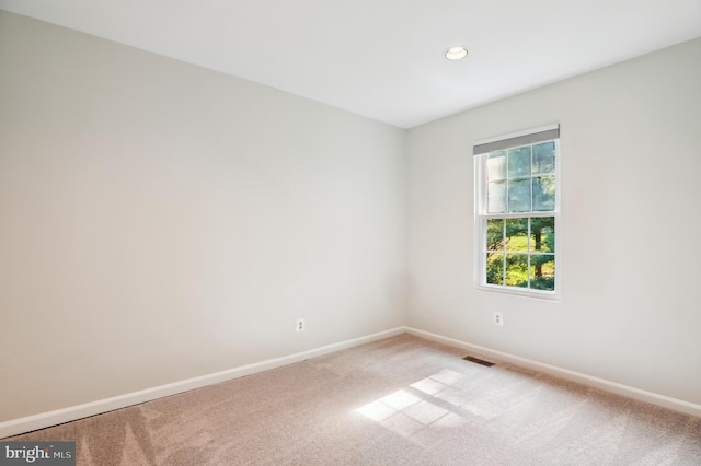 spare room featuring recessed lighting, light colored carpet, visible vents, and baseboards