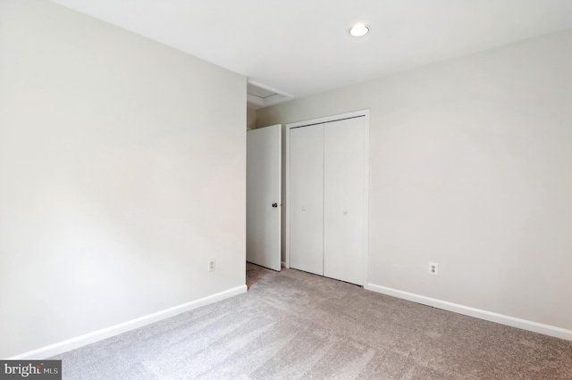 unfurnished bedroom with light carpet, attic access, baseboards, a closet, and recessed lighting