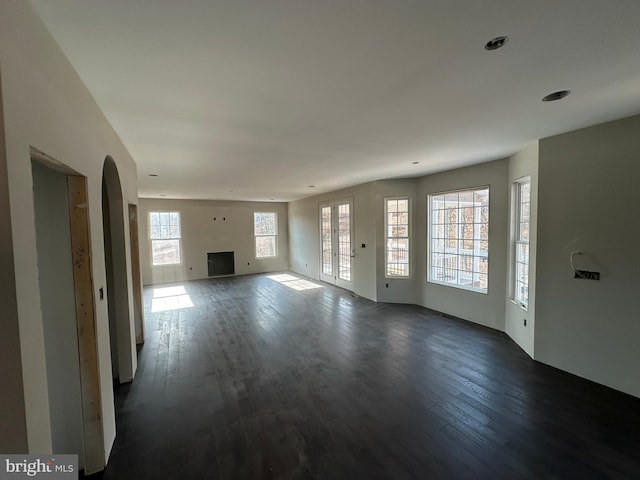 unfurnished living room with dark hardwood / wood-style flooring and a healthy amount of sunlight