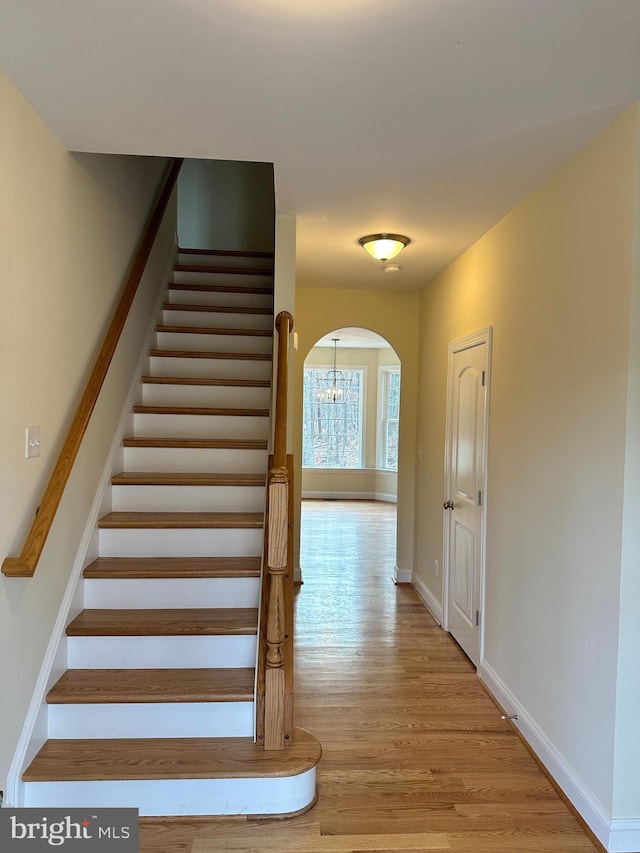 stairway featuring hardwood / wood-style flooring and an inviting chandelier