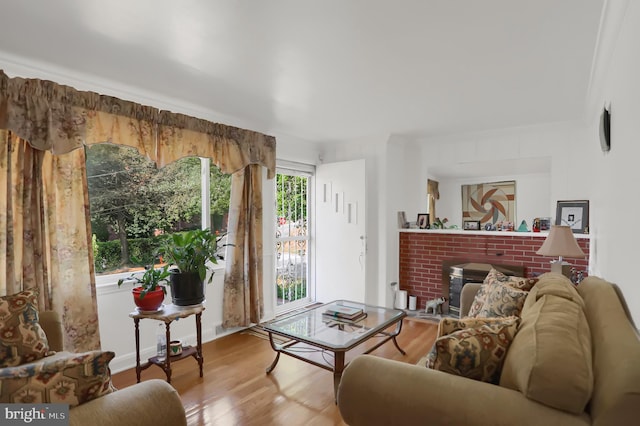 living room with a brick fireplace, ornamental molding, and light hardwood / wood-style floors