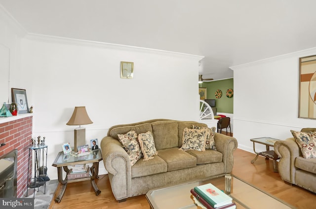 living room featuring a brick fireplace, ornamental molding, and light wood-type flooring