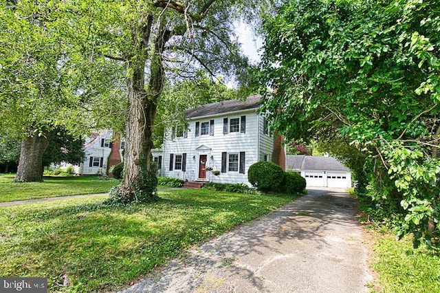 view of front facade featuring a garage, an outbuilding, and a front lawn