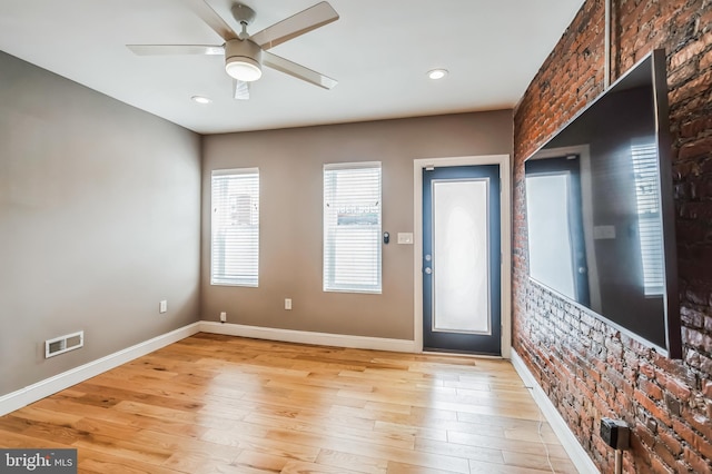 entrance foyer with ceiling fan, brick wall, and light hardwood / wood-style flooring