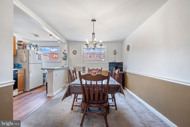 dining space with hardwood / wood-style floors and an inviting chandelier