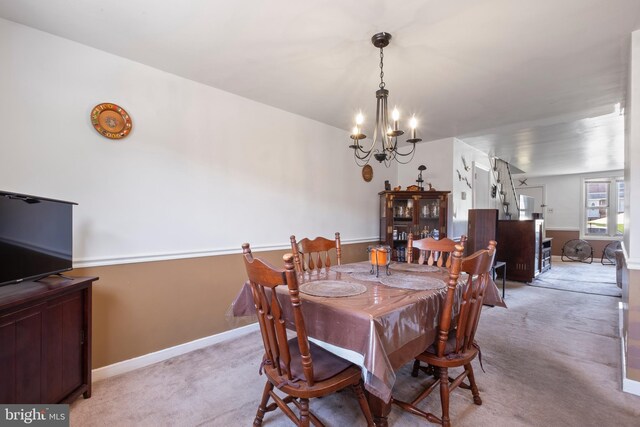 dining space featuring light carpet and a notable chandelier