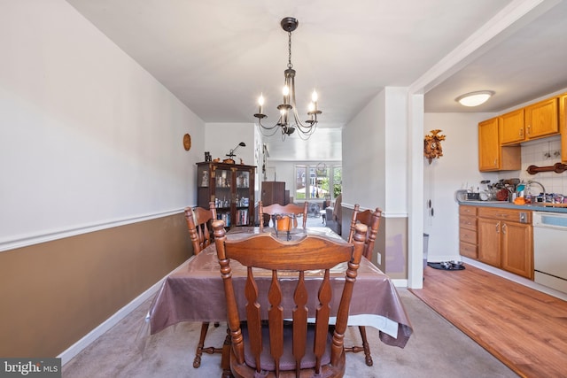 dining room with sink, a chandelier, and light hardwood / wood-style floors