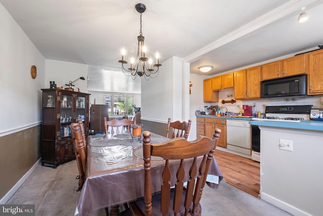 dining space with light hardwood / wood-style flooring, sink, and an inviting chandelier