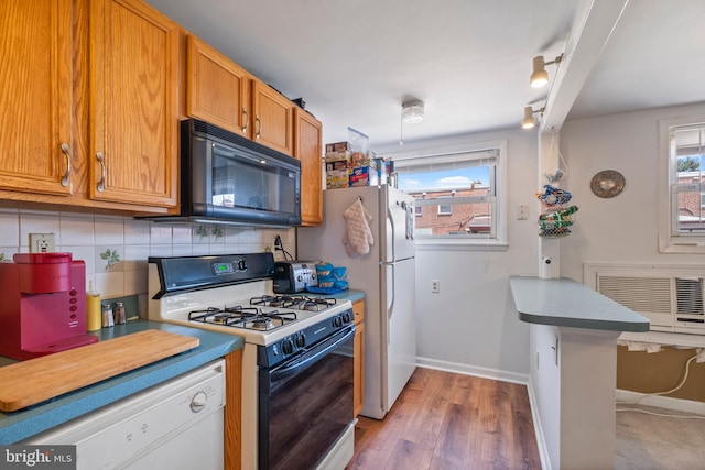 kitchen with track lighting, white appliances, kitchen peninsula, backsplash, and wood-type flooring