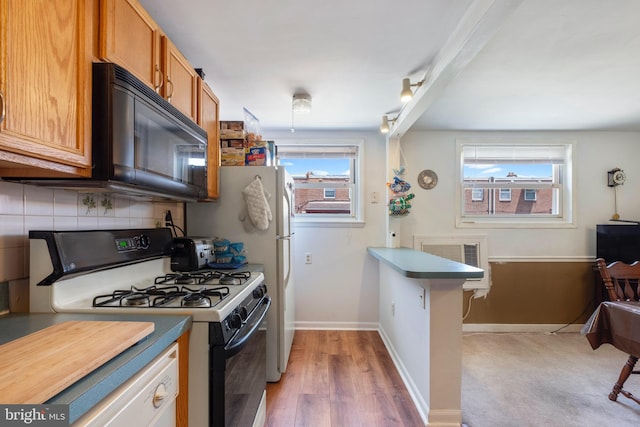 kitchen with backsplash, hardwood / wood-style floors, and white gas range