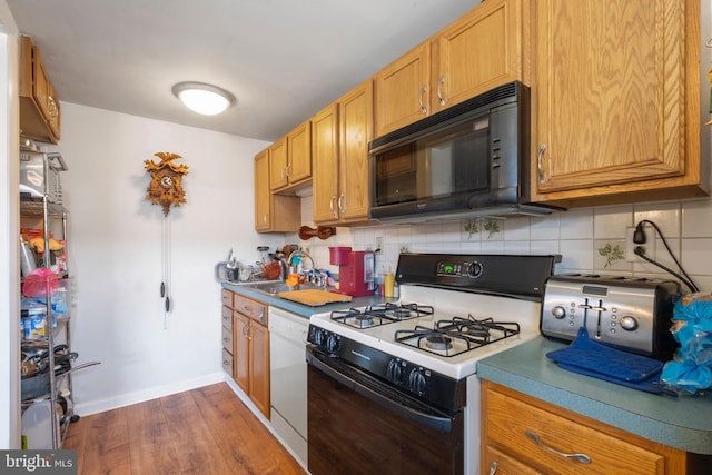 kitchen featuring sink, dark hardwood / wood-style flooring, backsplash, and white appliances