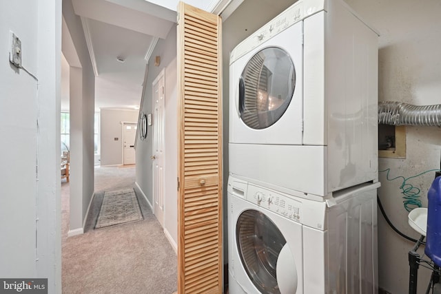 clothes washing area with crown molding, stacked washer / dryer, and light carpet