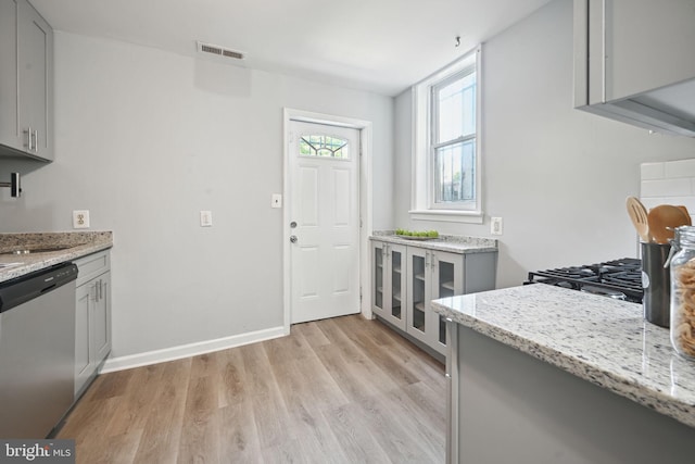 kitchen featuring light stone counters, gray cabinets, dishwasher, and light hardwood / wood-style flooring