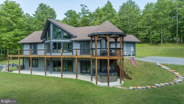 rear view of property featuring a wooden deck, a patio, and a lawn