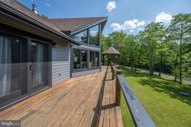 wooden terrace featuring a lawn and a gazebo