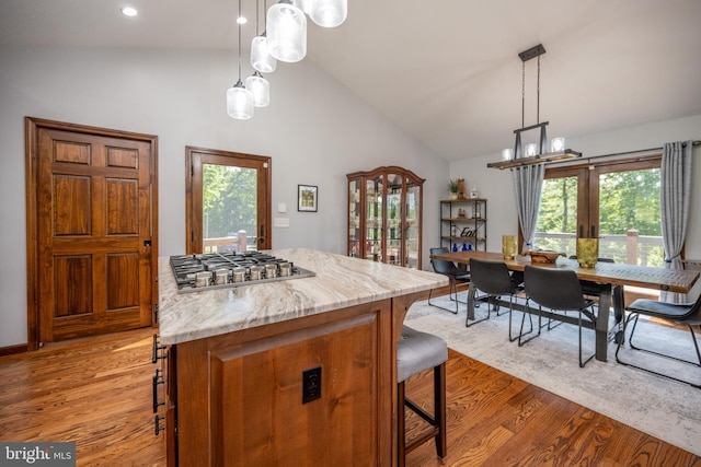 kitchen featuring light hardwood / wood-style floors, a breakfast bar area, a wealth of natural light, and light stone countertops