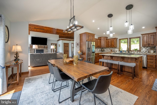 dining room with a fireplace, dark wood-type flooring, and high vaulted ceiling