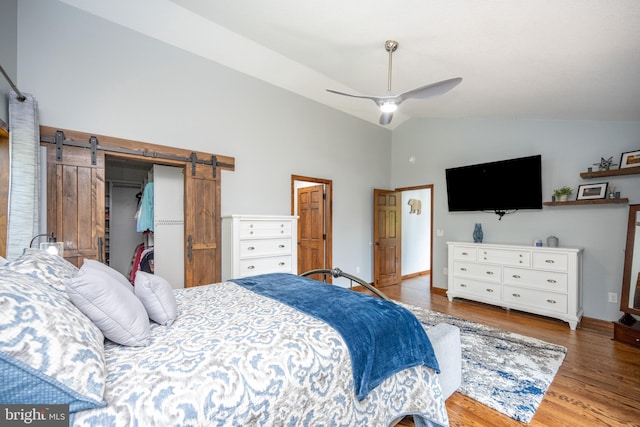 bedroom featuring a closet, ceiling fan, hardwood / wood-style floors, a barn door, and lofted ceiling