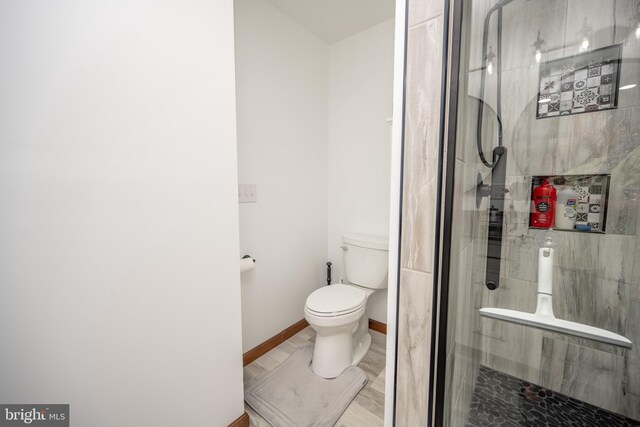 bathroom with tile patterned flooring, a tile shower, and toilet