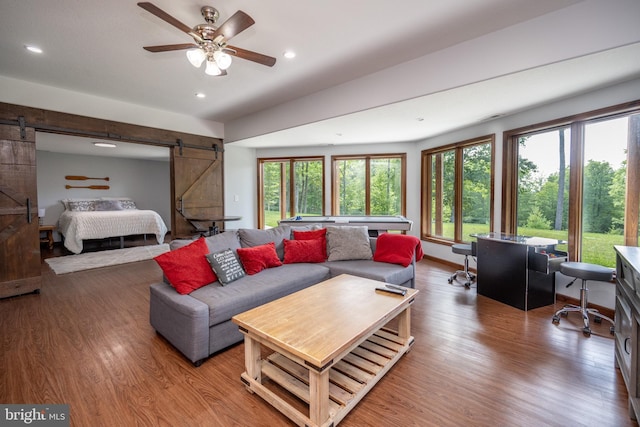 living room featuring hardwood / wood-style floors, ceiling fan, and a barn door