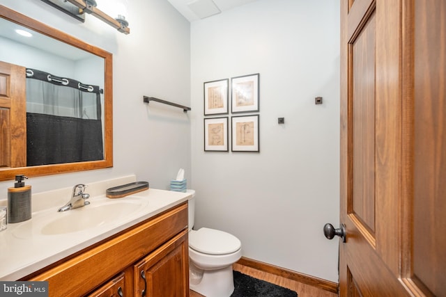 bathroom with hardwood / wood-style flooring, toilet, and vanity