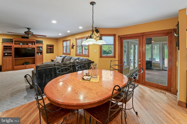 dining area with ceiling fan, french doors, and light wood-type flooring