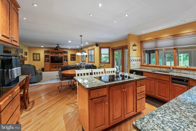 kitchen with light hardwood / wood-style floors, sink, decorative backsplash, and a healthy amount of sunlight