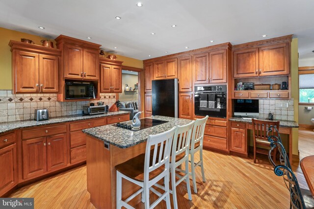 kitchen featuring a kitchen island, light hardwood / wood-style floors, black appliances, and tasteful backsplash