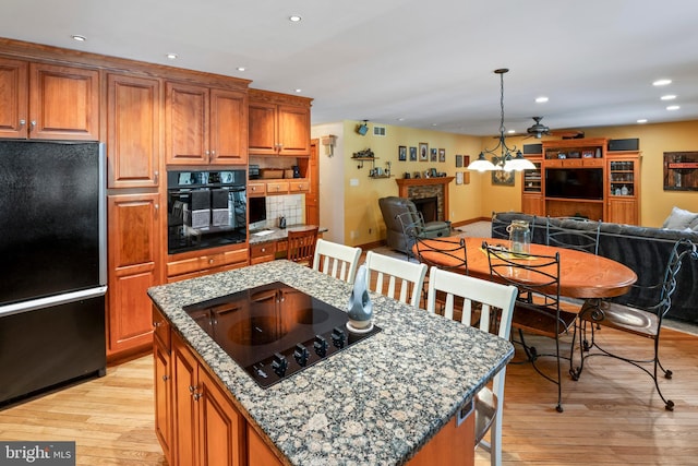 705 Franklinville Rd, Mullica Hill, NJ 08062 - kitchen featuring a fireplace, a kitchen island, open floor plan, brown cabinets, and black appliances