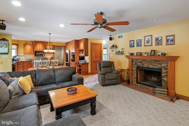 living room featuring ceiling fan, a fireplace, and light hardwood / wood-style flooring