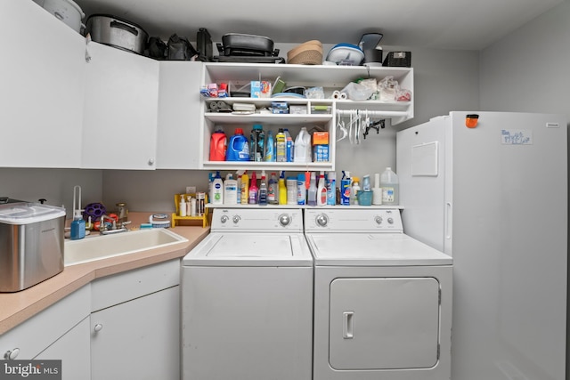 washroom featuring sink, washing machine and clothes dryer, and cabinets